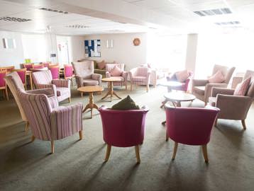 Armchairs in a circle with coffee tables in resident's communal lounge