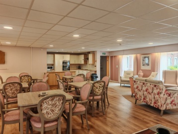 An open lounge, with dinning tables and chairs, sofa style seating, and a small kitchenette