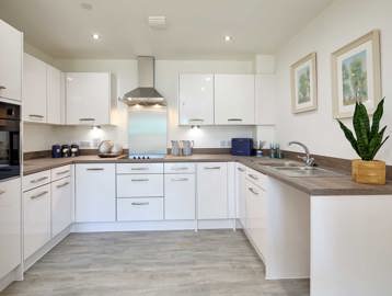 A kitchen inside an apartment at Filey Fields featuring white cupboards, with brown wood worktops 