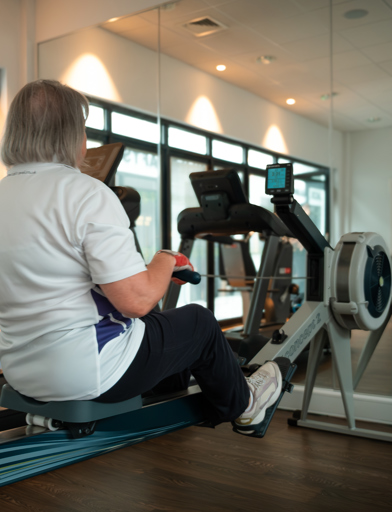 A female resident using the rowing machine in the gym at Lime Gardens 