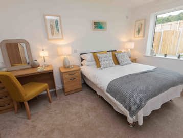 A photo of a bedroom with a double bed, side table and dressing table at Castlestead View