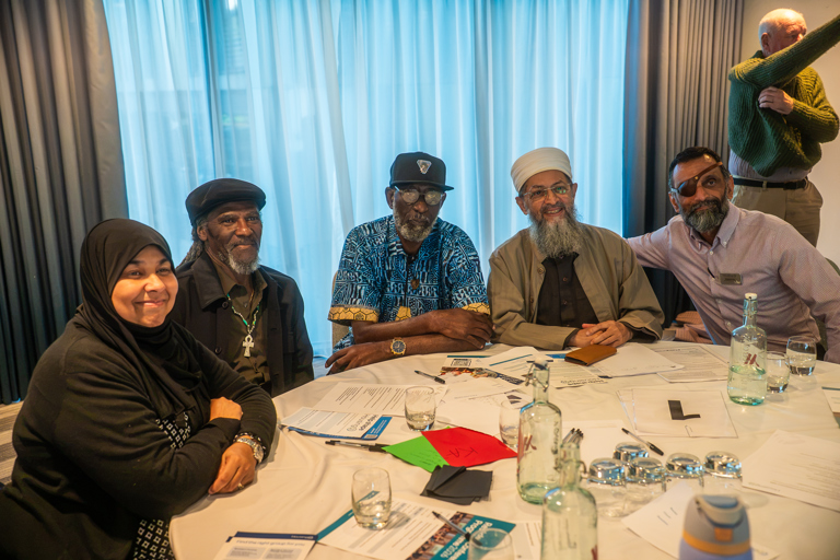 Three cohousing residents sit with two Housing 21 colleagues and smiling during the conference