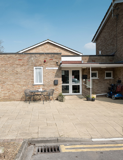 Main entrance to the scheme with patio area, tables and chairs 