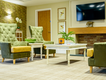 Residents' lounge with soft seating and wall-mounted TV