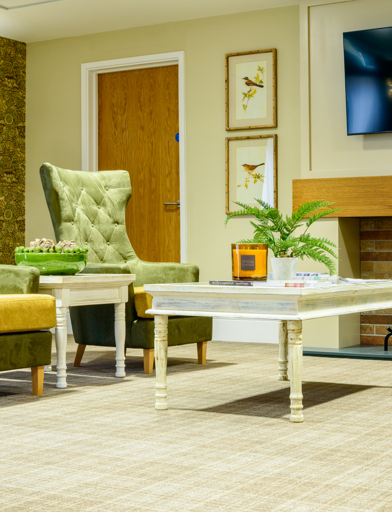 Residents' lounge with soft seating and wall-mounted TV 