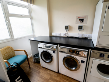 A small communal laundry room with washing machines and a dryer