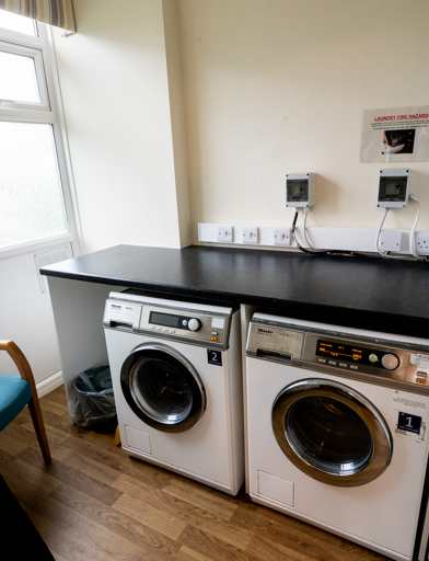 A small communal laundry room with washing machines and a dryer