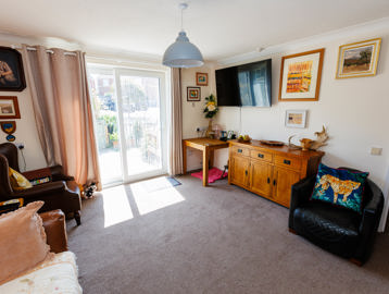 Spacious lounge with wall-mounted television and sliding glass doors leading out to the garden.