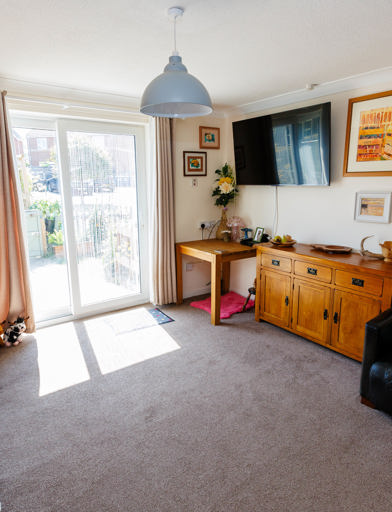 Spacious lounge with wall-mounted television and sliding glass doors leading out to the garden. 