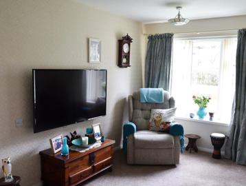 Living room area in a resident's apartment with armchair and TV