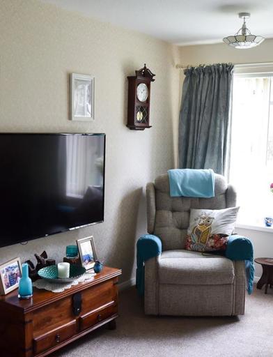 Living room area in a resident's apartment with armchair and TV 