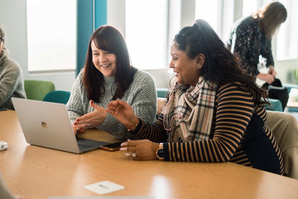 Corporate employees smiling looking at a laptop