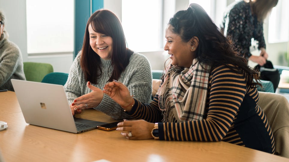 Corporate employees smiling looking at a laptop