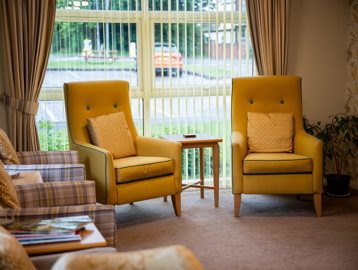 Comfy yellow arm chairs situated in the communal lounge