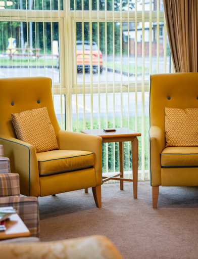 Comfy yellow arm chairs situated in the communal lounge 