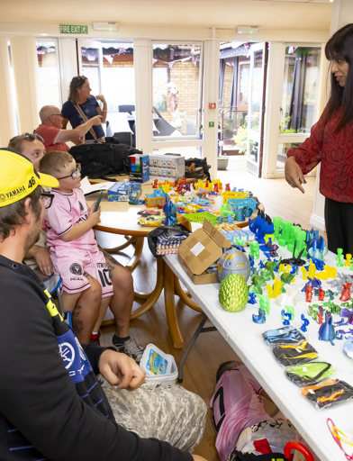 MP Sureena Brackenridge in conversation with a child at a stall which is selling lots of colourful figurines 