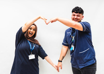 Two Care Workers creating a heart with their arms smiling 