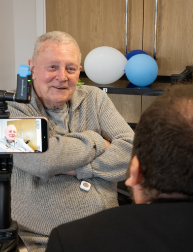 Resident being interviewed, speaking to a man behind a video camera 