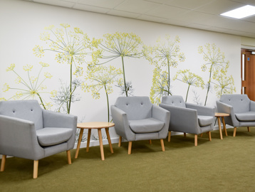 Communal area with soft seating and floral wallpaper inside Acre Court