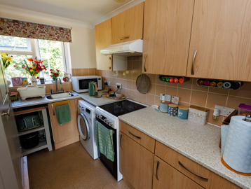 Kitchen with fitted units, storage space, washing machine, small double oven, and window overlooking the garden