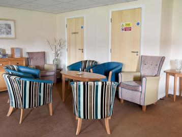 A communal seating area for residents with soft seated armchairs