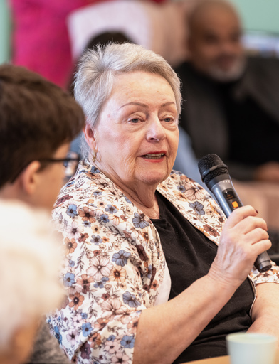 Lady sat at a table talking into a microphone 