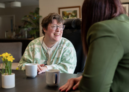 a woman smiles whilst in conversation with another woman