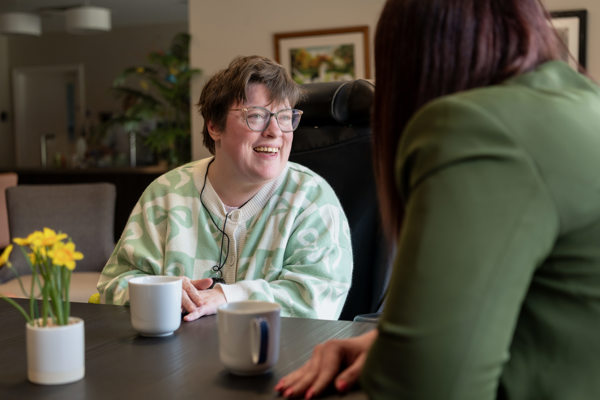 a woman smiles whilst in conversation with another woman