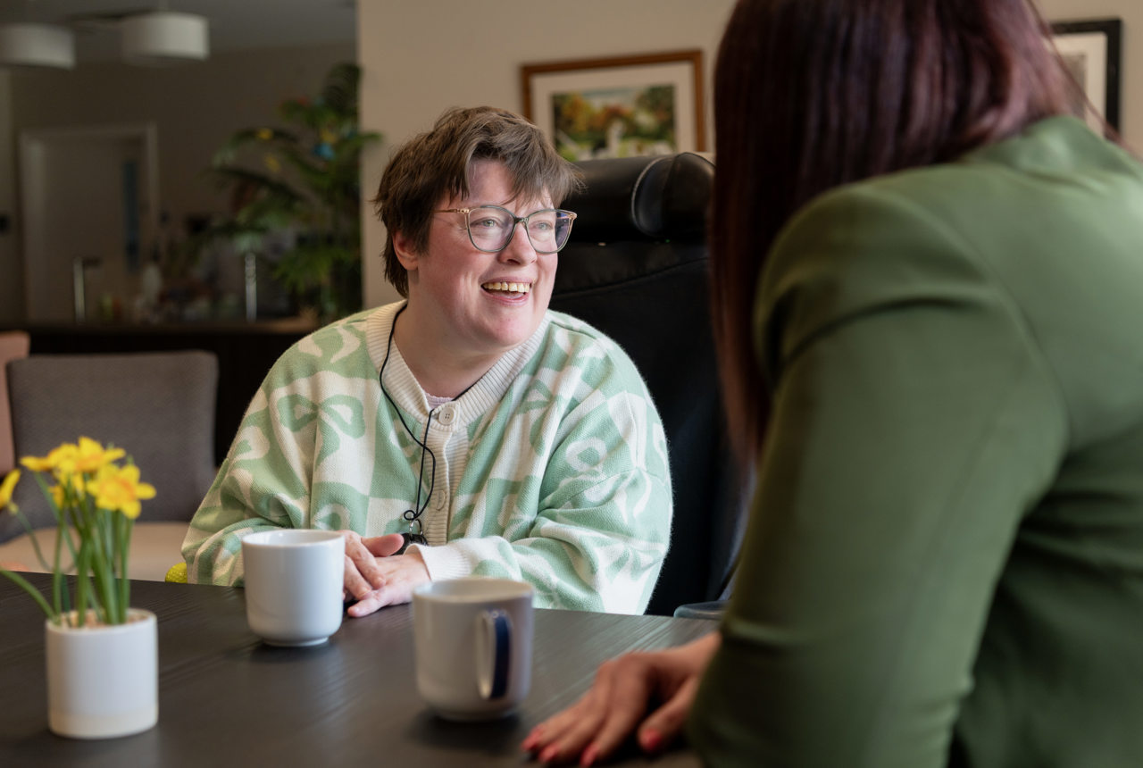 a woman smiles whilst in conversation with another woman