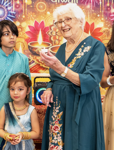 Elderly resident holding a candle and posing at a Diwali celebration 