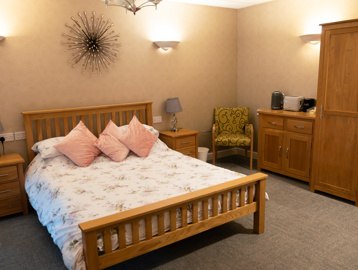 A double bed with wardrobe side tables and soft furnishings in the guest room