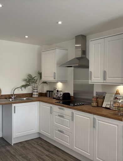 A kitchen with white cupboards featuring brown wooden flooring and a brown counter top 