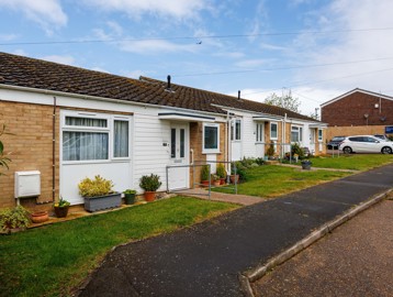 The front of a bungalow, pots, plants and shrubs