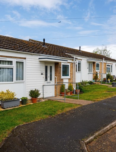The front of a bungalow, pots, plants and shrubs 