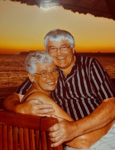 A couple hugging and posing while on holiday in front of a sunset 