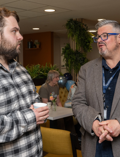 Two men in discussion inside a communal lounge 