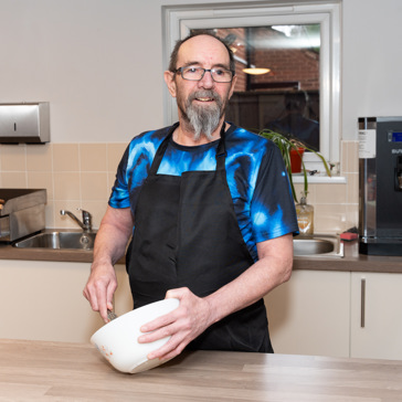 Resident with a mixing bowl in a kitchen