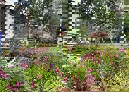 A close up photograph of the flowers and plants in the rear garden with water fountain and seating