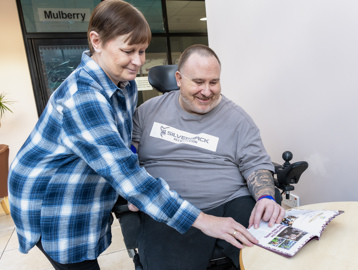 Chris, a Housing 21 resident, looks at an Aston Villa football programme with his sister, Wendy
