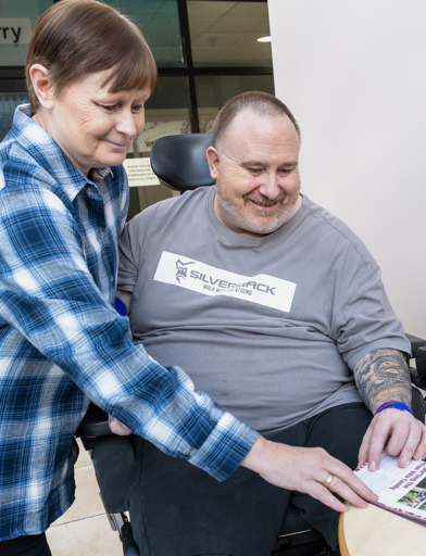 Chris, a Housing 21 resident, looks at an Aston Villa football programme with his sister, Wendy 