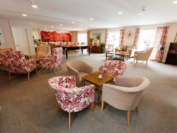 Communal lounge with a beige and red colour theme with comfortable chairs and tables