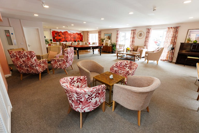 Communal lounge with a beige and red colour theme with comfortable chairs and tables