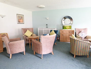Soft seating and tables in a communal area with a large mirror and fish tank