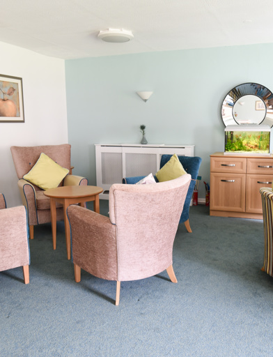 Soft seating and tables in a communal area with a large mirror and fish tank