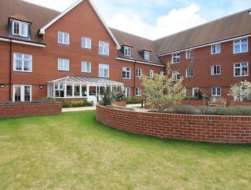 Side view of the rear garden area with grassed section, seating and conservatory