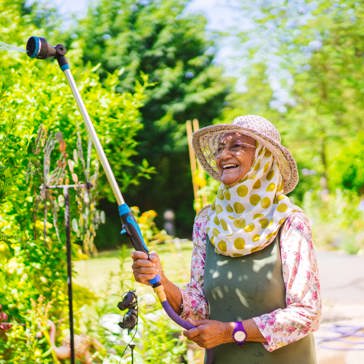 Resident smiling in a garden watering plants 