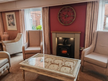 A communal seating area with armchairs around a fireplace