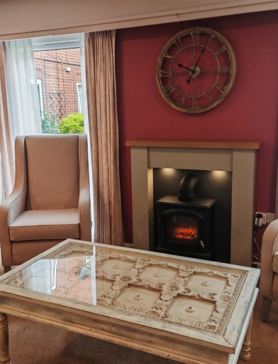 A communal seating area with armchairs around a fireplace 