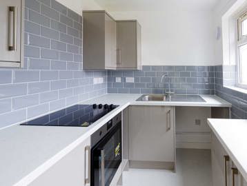 Modern kitchen with blue, grey tiles in an empty show apartment