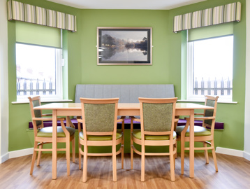 Communal dining table inside Acre Court with green painted walls